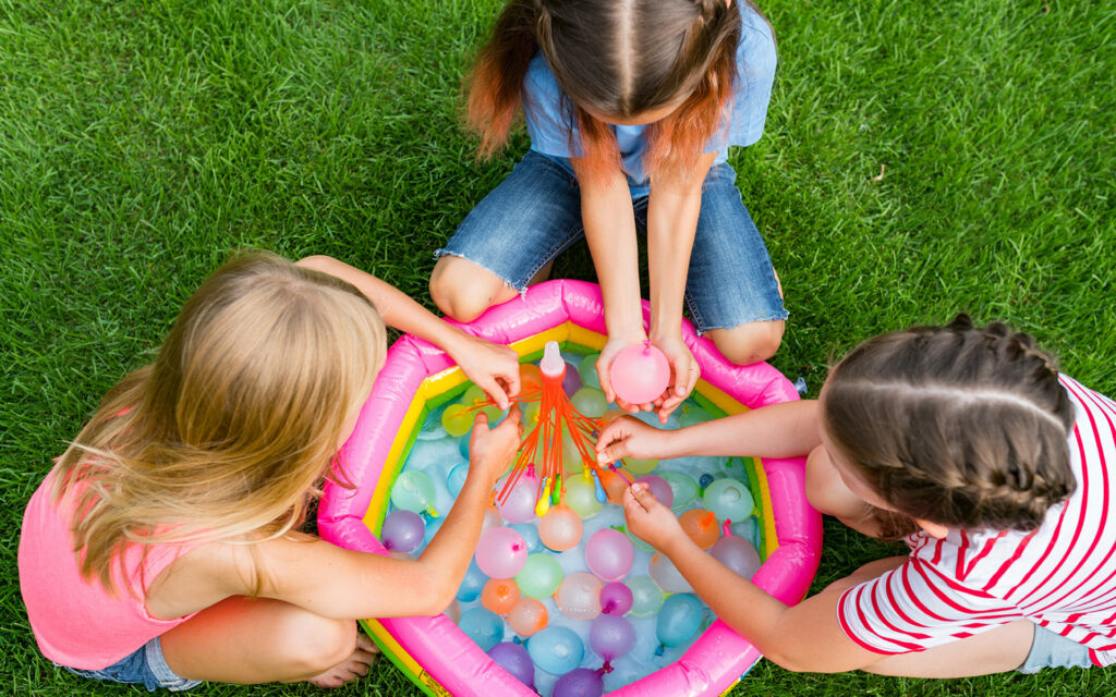 kids playing with water balloons in the yard